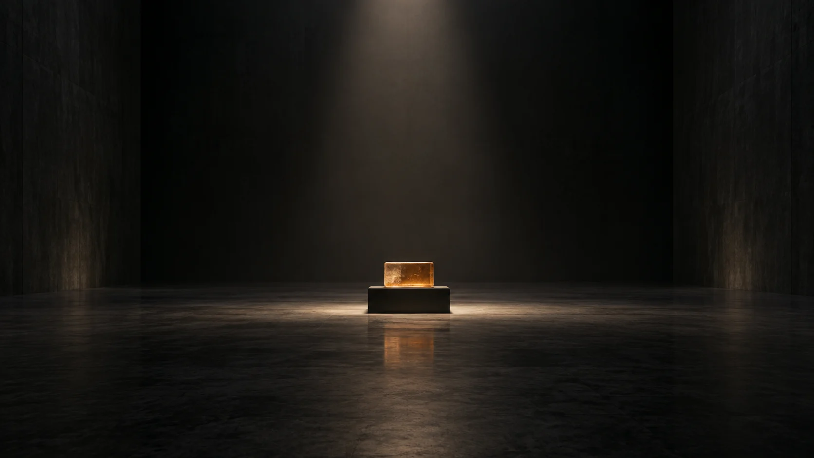 A small amber glass block sits alone on a black plinth in a vast, dark exhibition room.